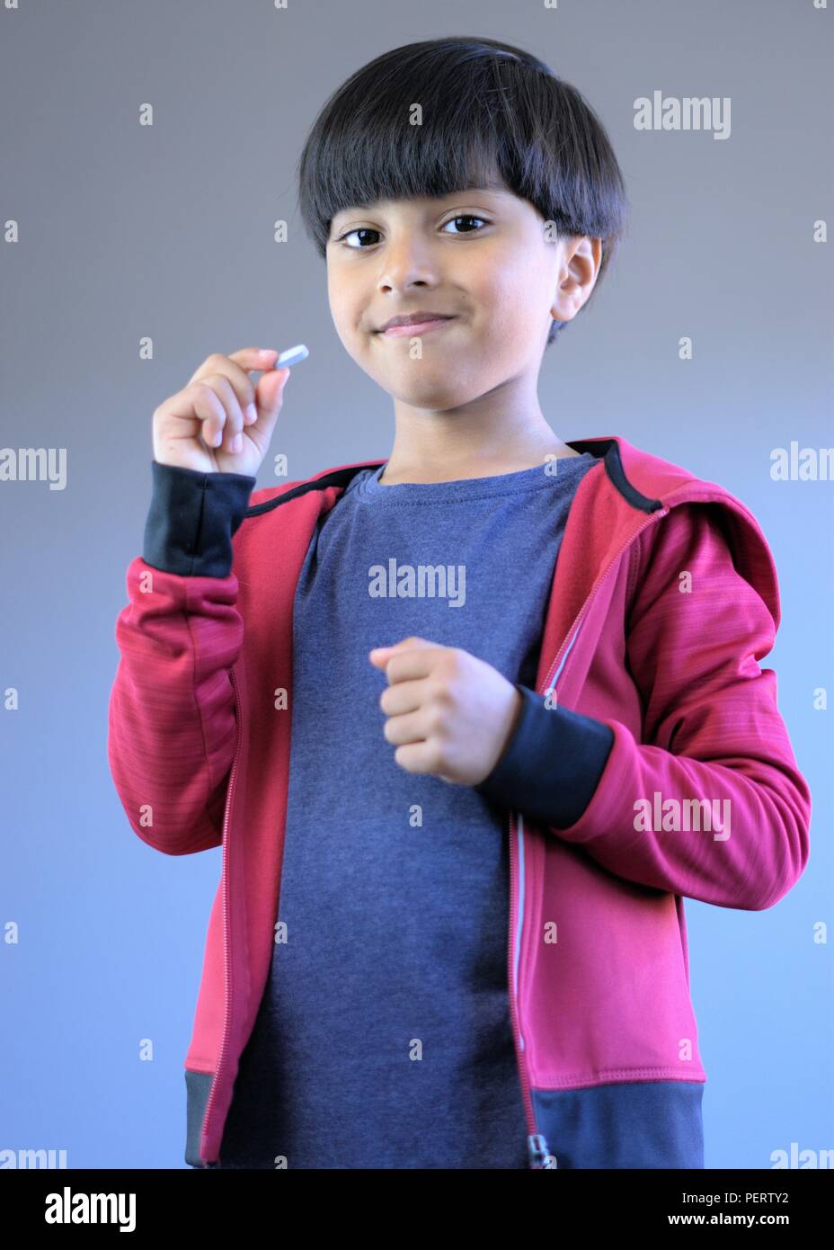 Portrait of smiling kid with pill in hand. Concept of happy kid ready to take medicine or vitamins. Stock Photo
