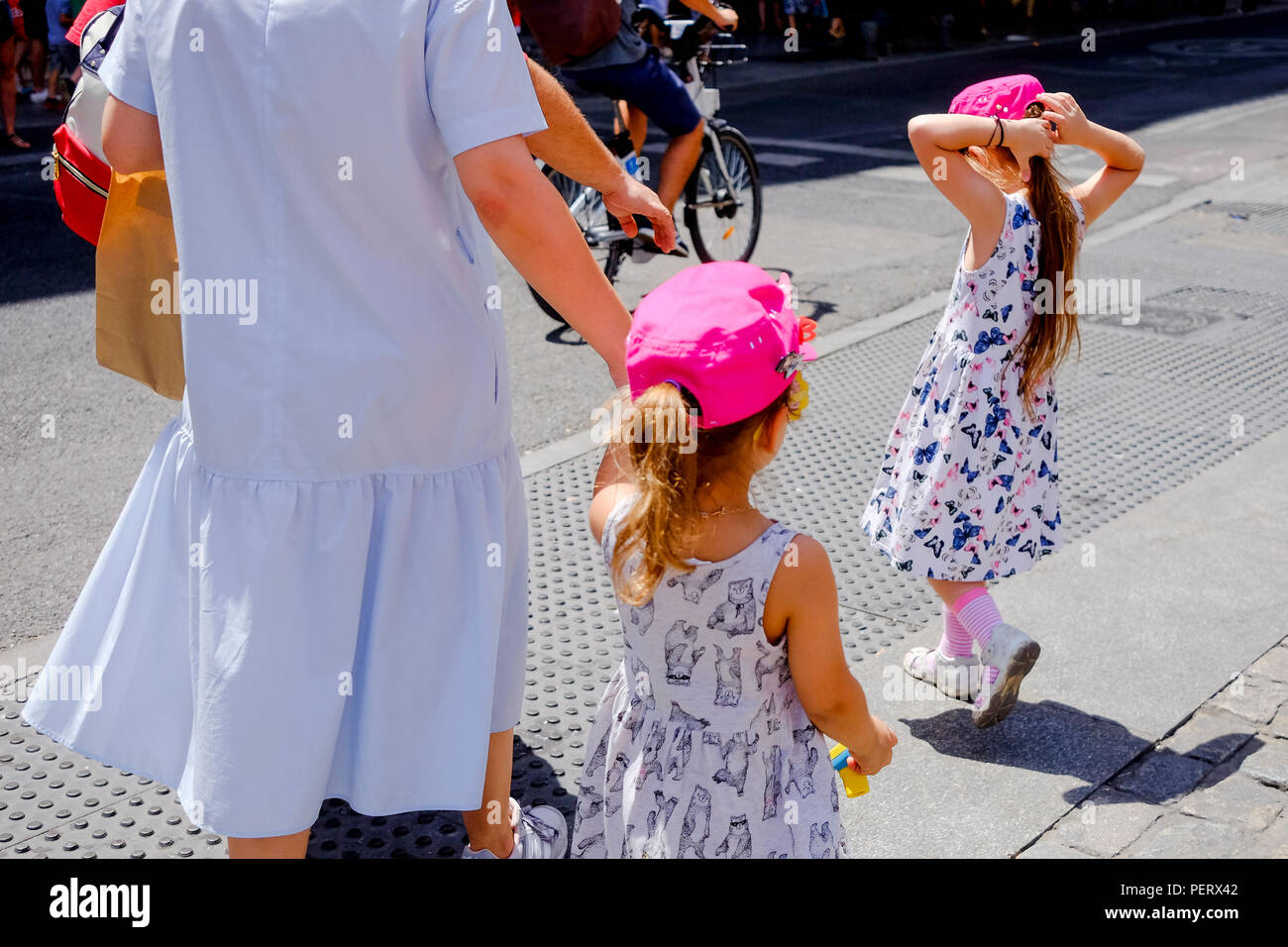 Two young girls with their parents wearing a pink cap in the hot August sun in Sol Madrid Spain. Stock Photo