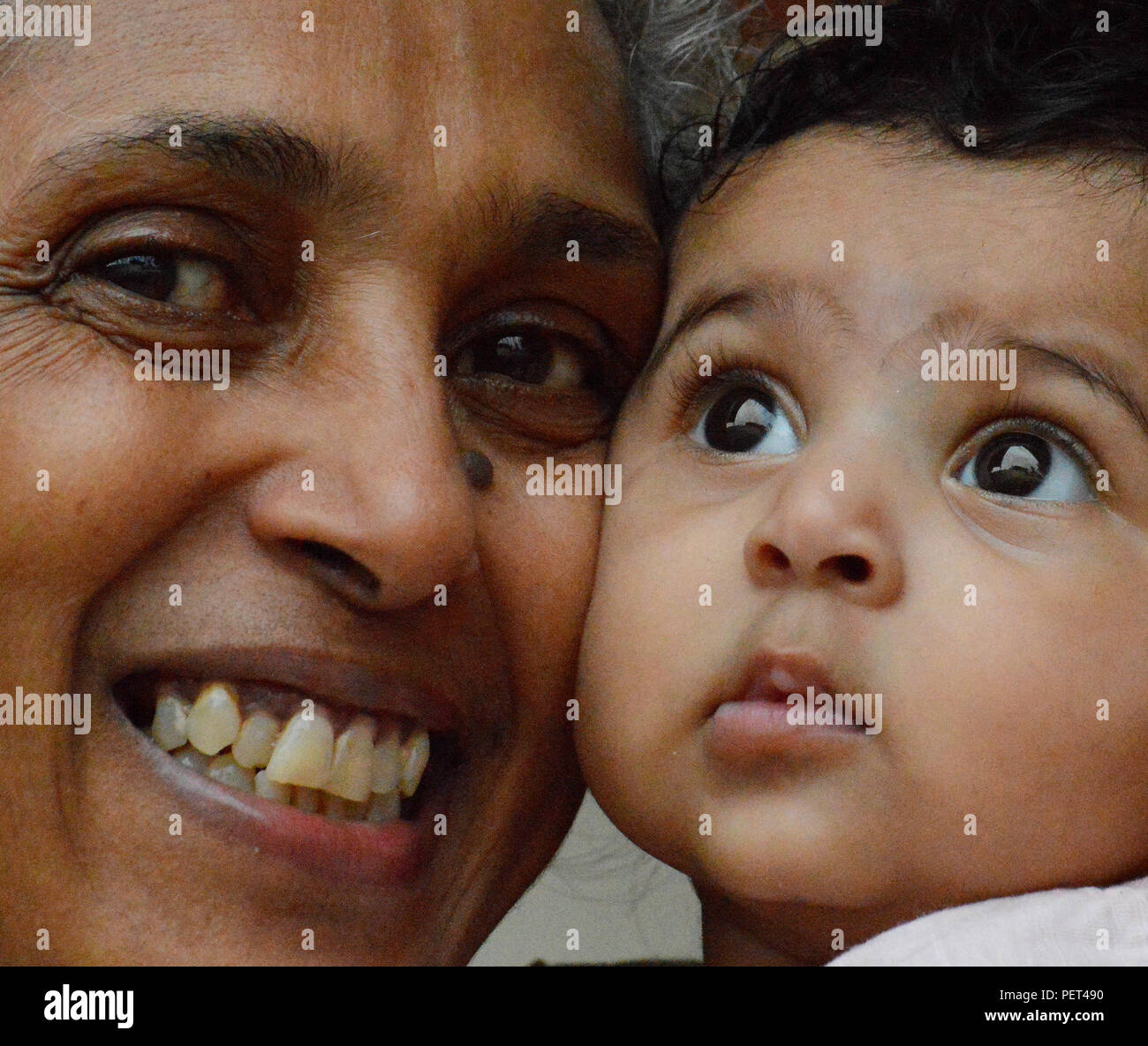 Close up of a granny with big broad smile hugging and holding her sweet princess tightly close to her face. Stock Photo