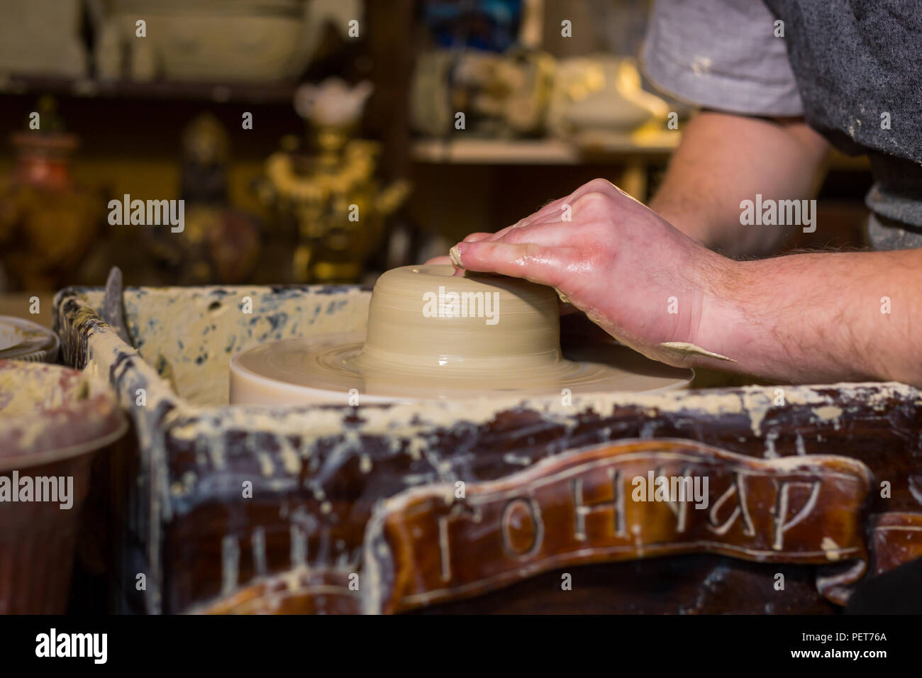 Professional male potter working with clay on potter's wheel in ...