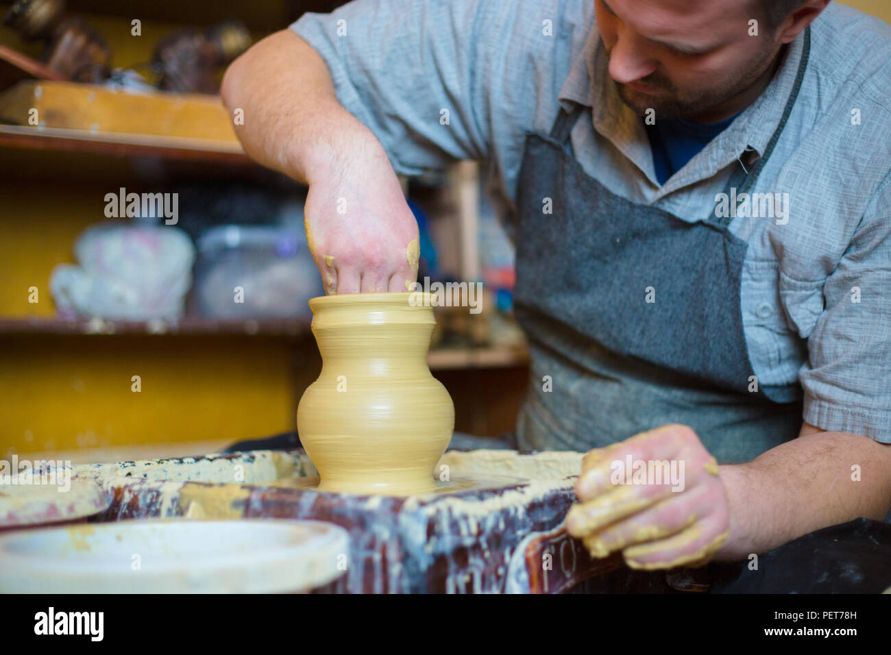 Professional male potter working with clay on potter's wheel in