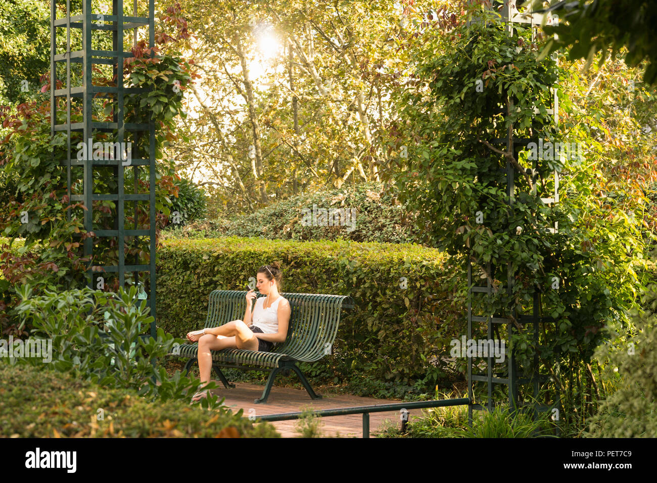 Paris greenery and urban garden - Young woman talking on phone at the Promenade plantee elevated park in the 12th arrondissement of Paris, France. Stock Photo