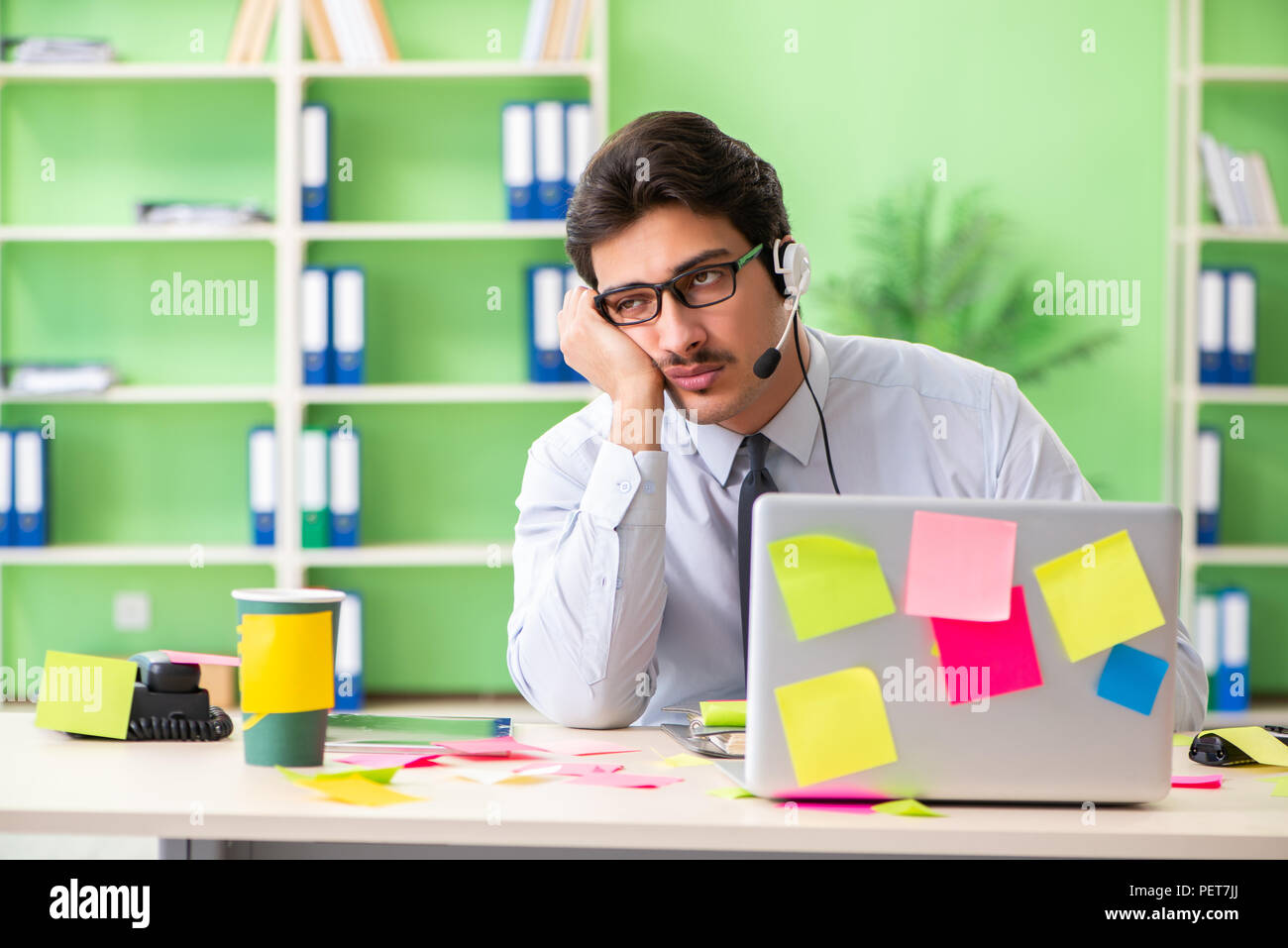 Young help desk operator working in office with many conflicting