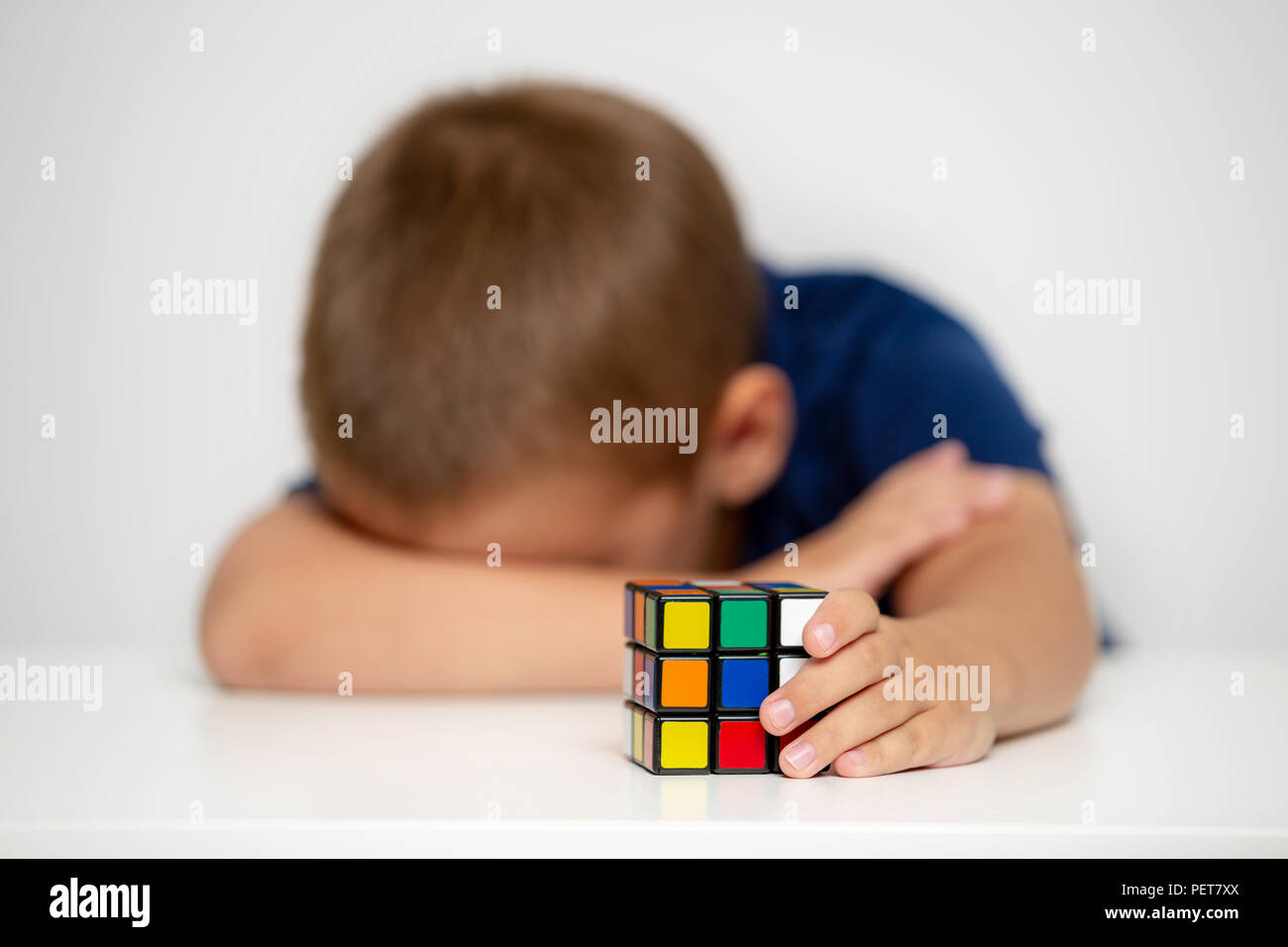 The child did not cope with the puzzle. The boy is crying because it was not possible to collect  cube Stock Photo