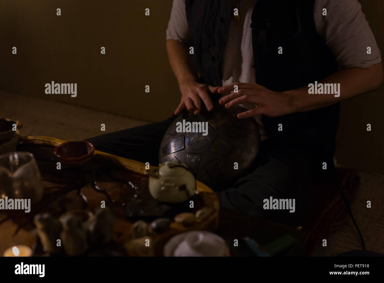 Man playing tank drum or hang at home. Warm romantic illumination, low key. Relaxation, meditative and traditional music concept. Close up shot Stock Photo