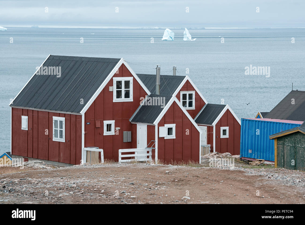 Red houses overlooking the Greenland Sea with icebergs in autumn