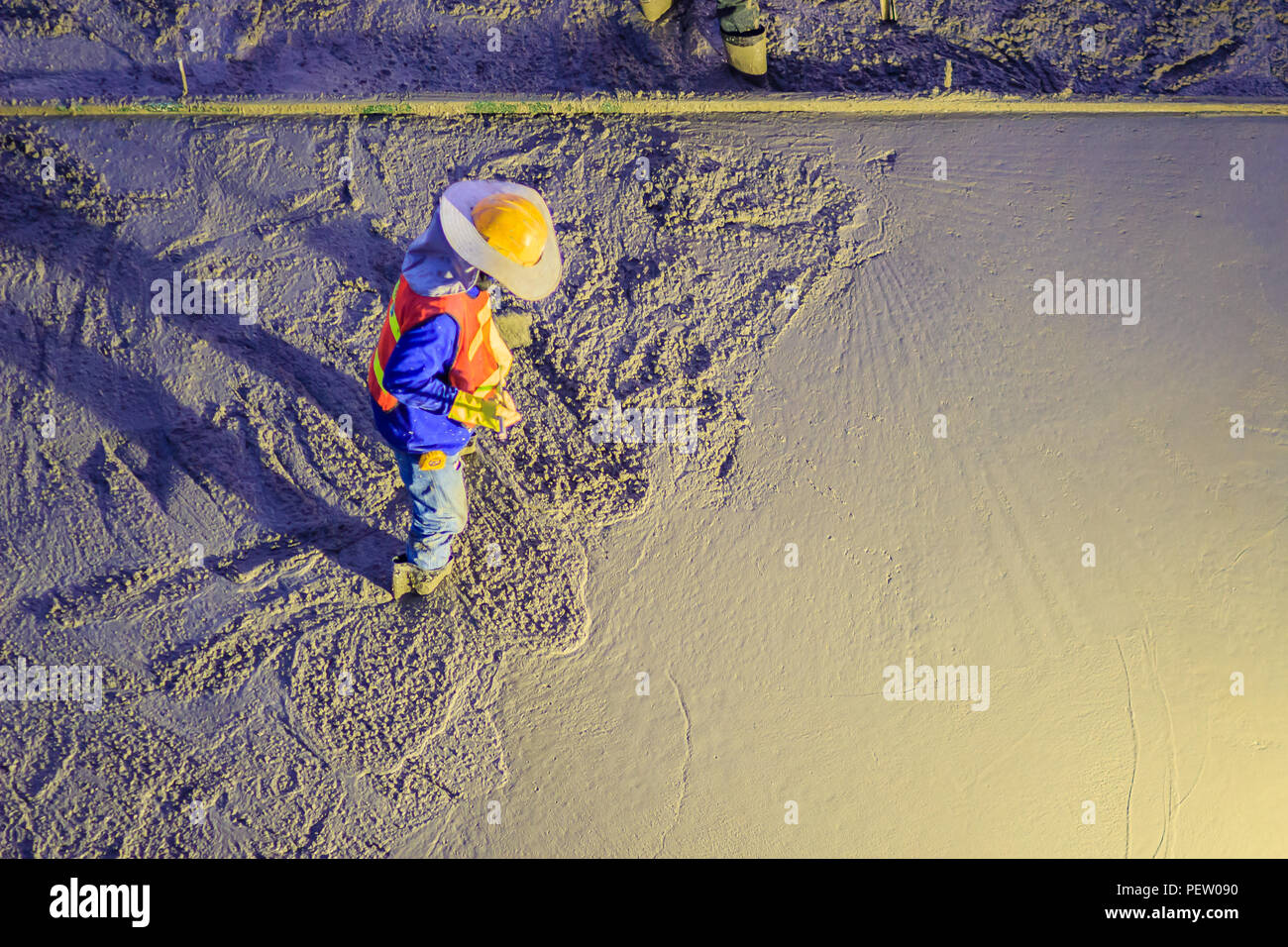 Mason worker leveling concrete with trowels, mason hands spreading poured concrete. Concreting workers are leveling poured liquid concrete on a steel  Stock Photo