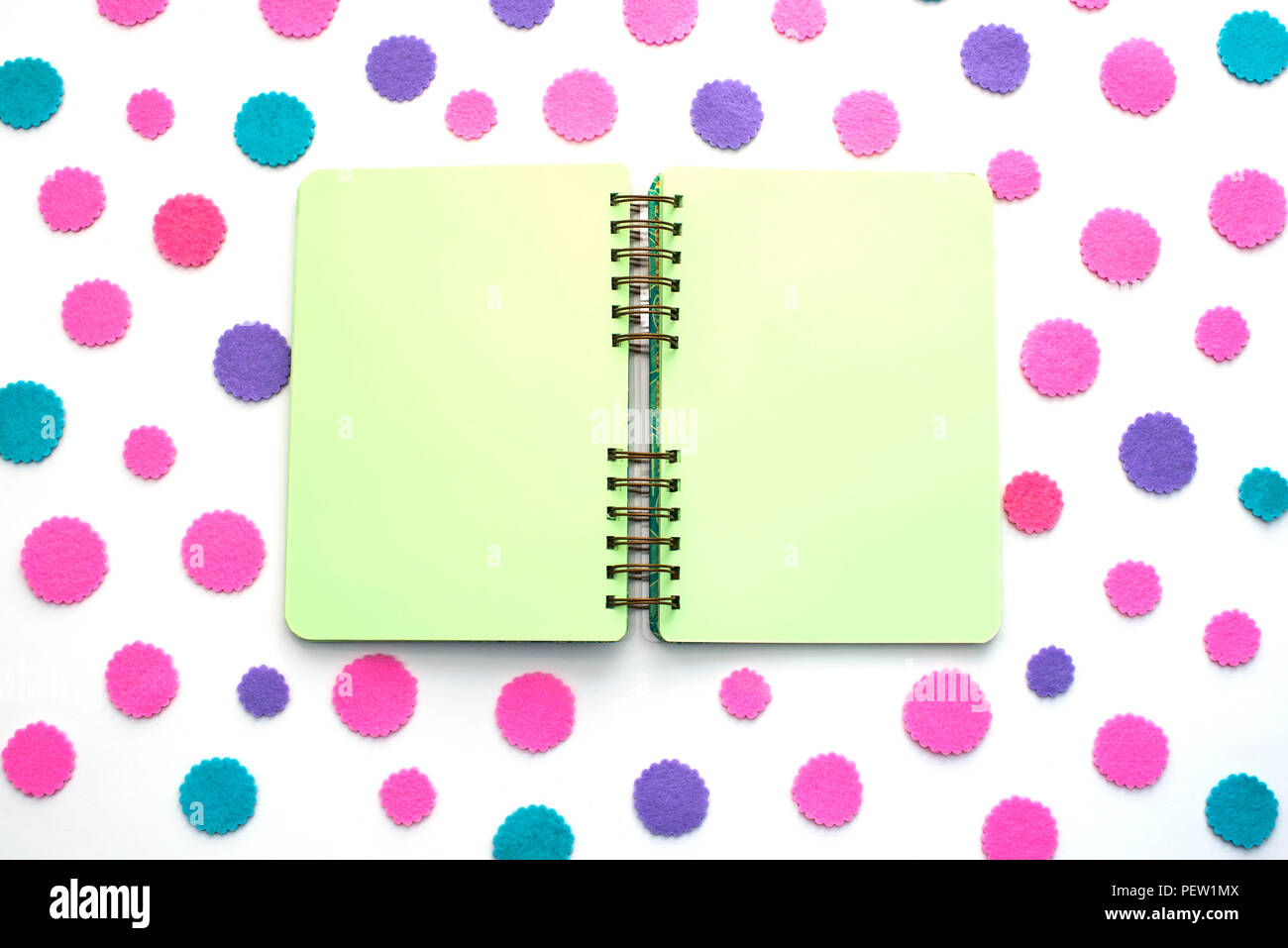 Open Notepad green pages on colored confetti background. Top view flat lay Stock Photo