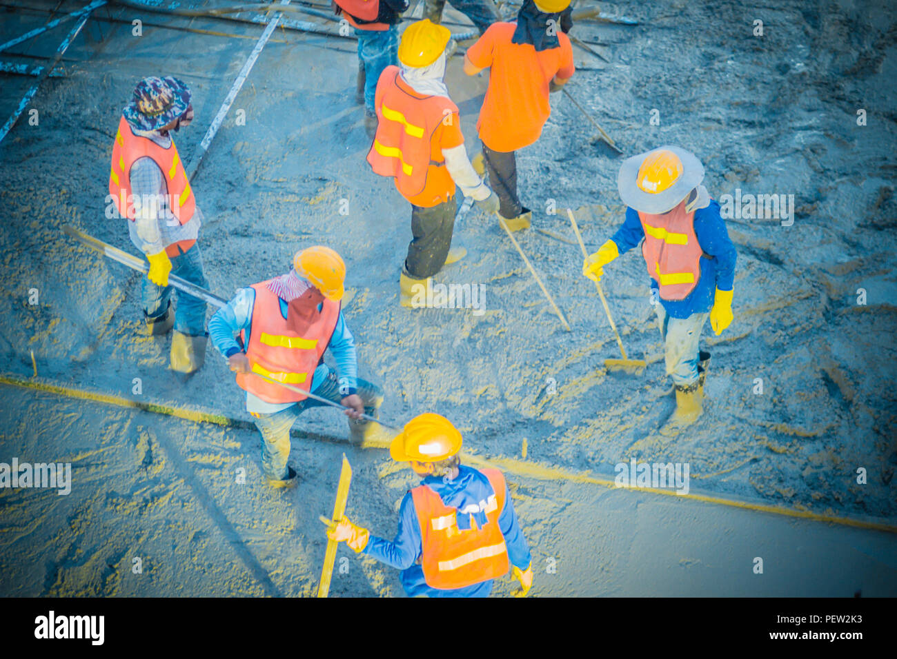 Concreting workers are leveling poured liquid concrete on a steel