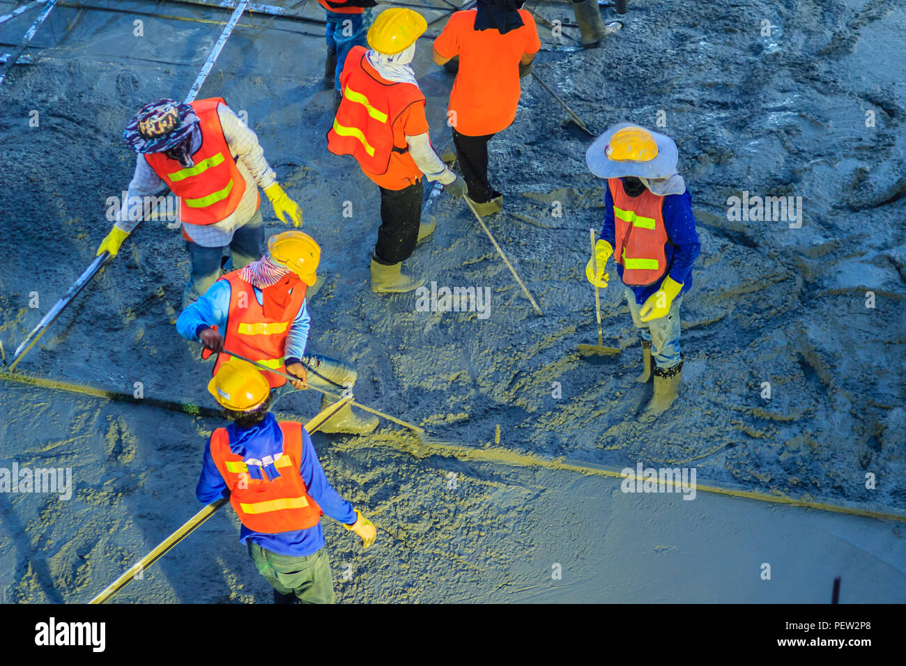 Concreting workers are leveling poured liquid concrete on a steel