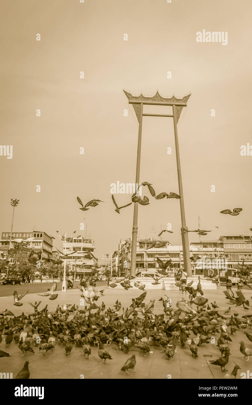 Vintage red giant swing or Sao Ching Cha with the crowd of pigeon, one of the most famous tourist attraction and landmark in Bangkok, Thailand. Stock Photo