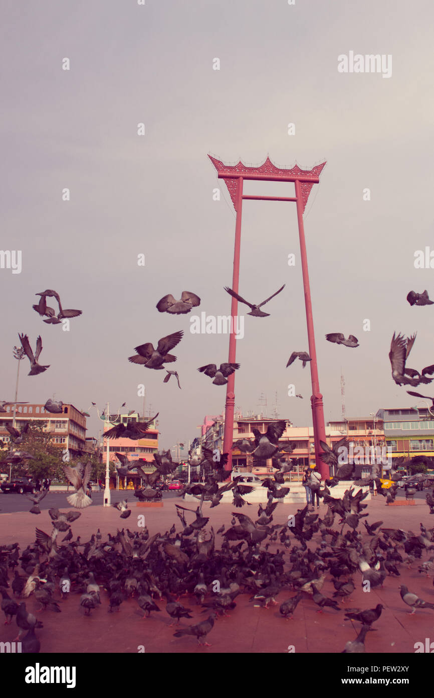 Vintage red giant swing or Sao Ching Cha with the crowd of pigeon, one of the most famous tourist attraction and landmark in Bangkok, Thailand. Stock Photo