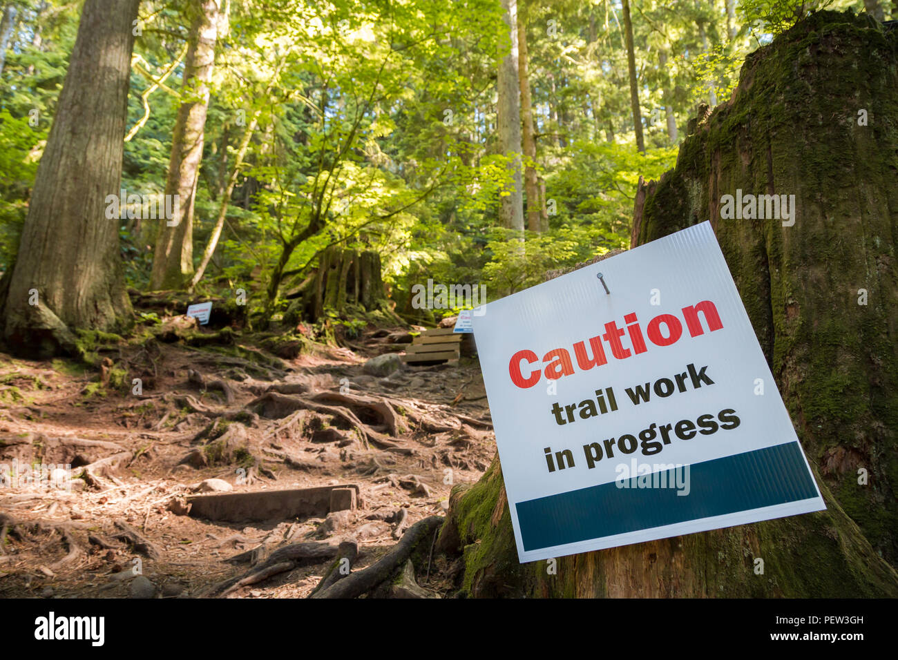 A caution sign next to a hiking trail. Stock Photo