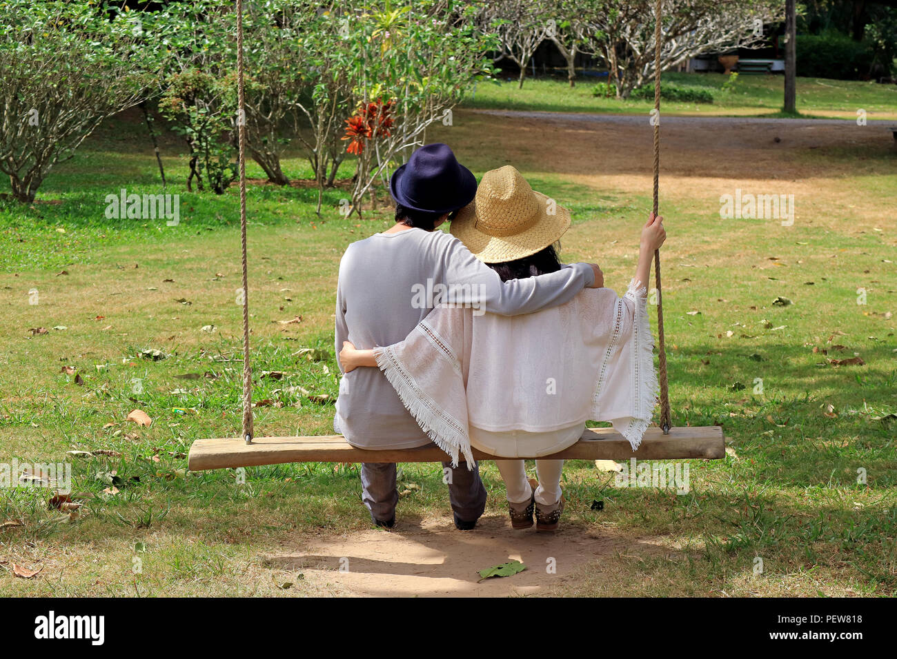 Young couple sitting side by side on a swing on in the public garden Stock Photo