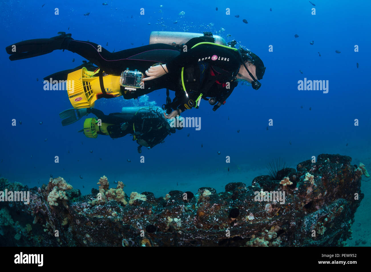 Two divers (MR) investigate a wreck off South Maui on underwater scooters that you can ride on.  Hawaii. Stock Photo