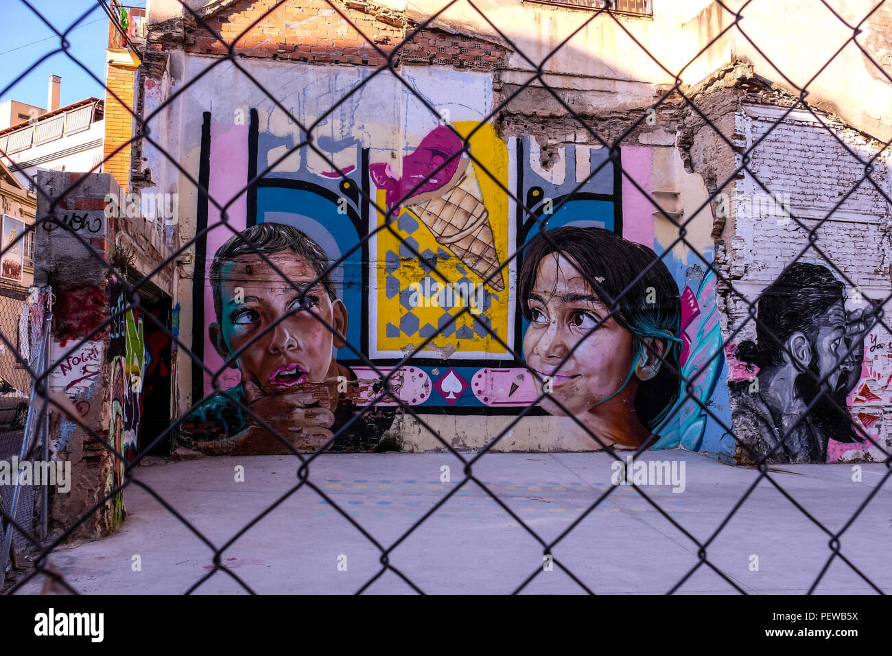 View of colorful street art, small kids behind a fence, shot in Malaga in Andalusia, Spain, near the plaza de la Merced Stock Photo
