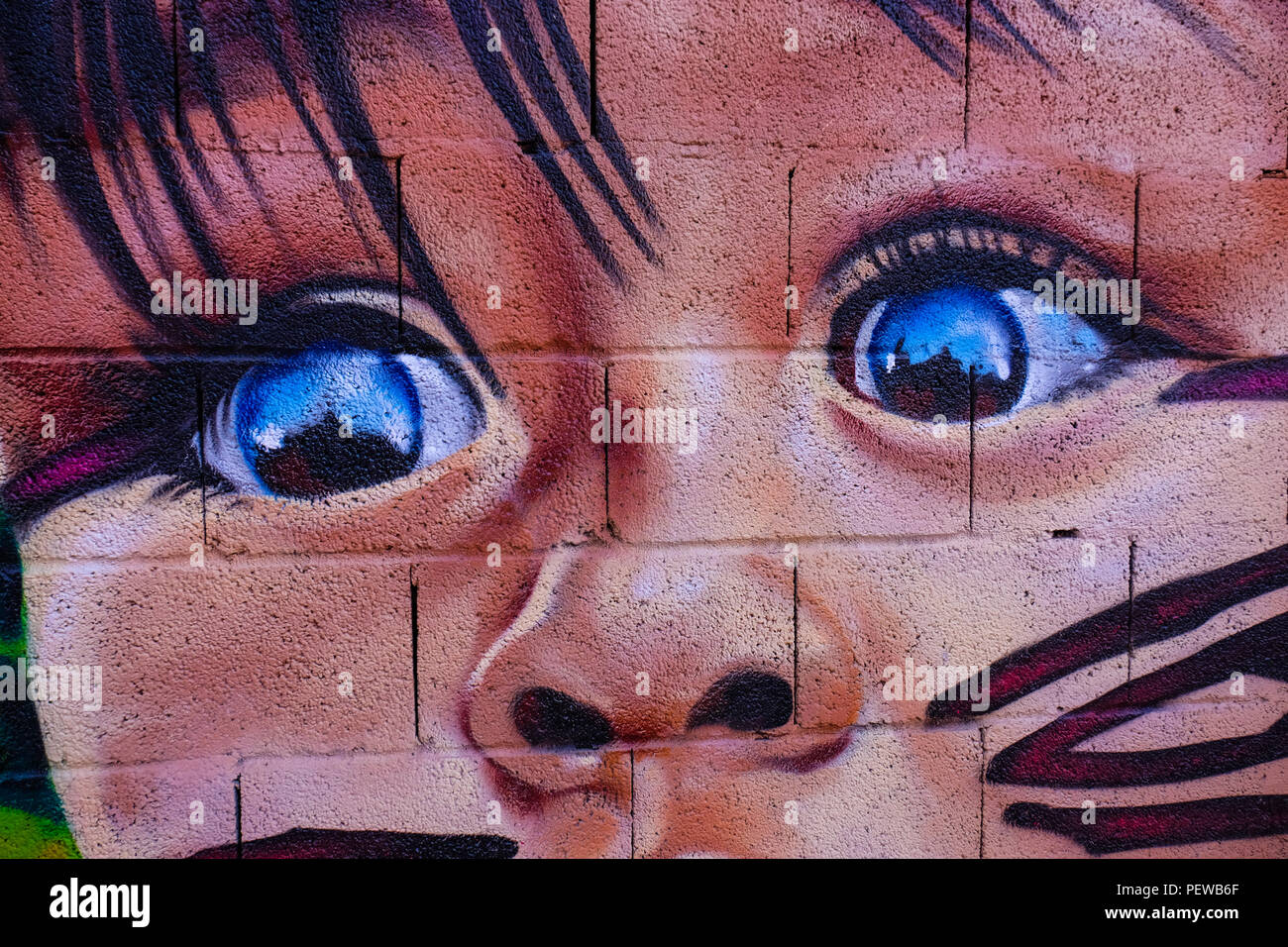 View of colorful street art, a small kid with blue eyes, shot in the streets of Malaga in Andalusia, Spain, near the plaza de la Merced Stock Photo