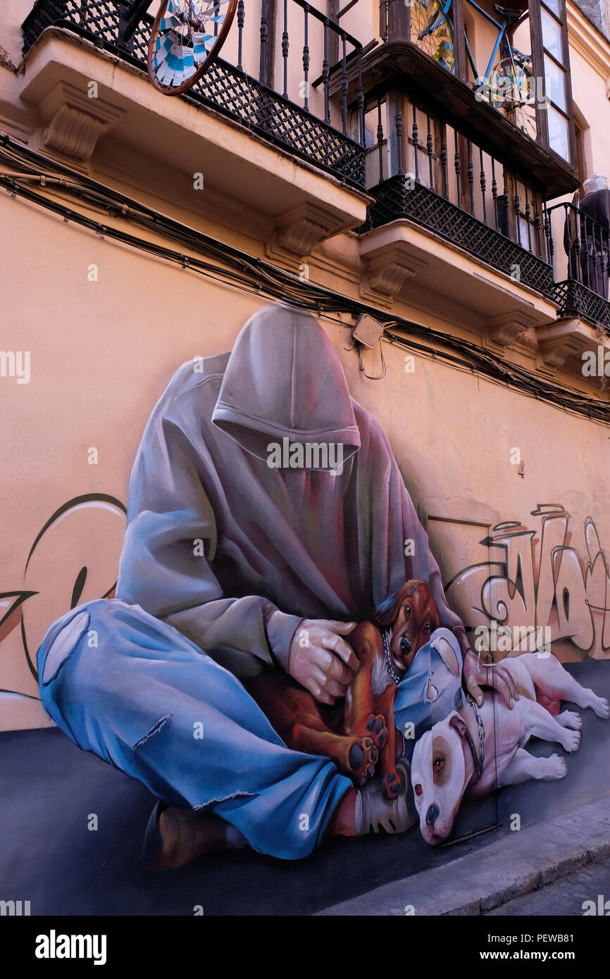 View of colorful street art, a man with a hoody and a dog, shot in the streets of Malaga in Andalusia, Spain, near the plaza de la Merced Stock Photo