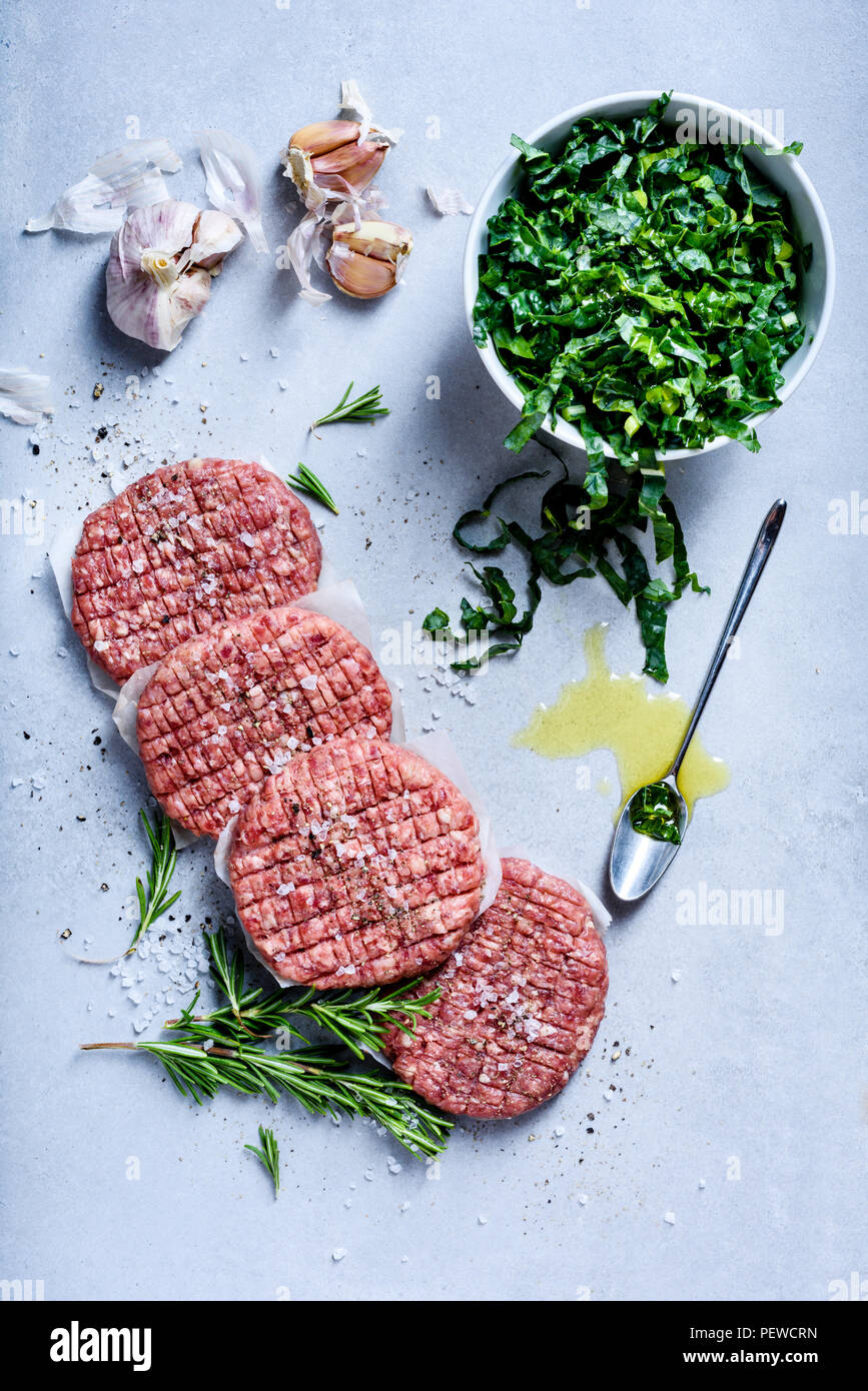 Raw burger cutlets, ground beef meat with salad and spices, hamburger ingredients. Top view
