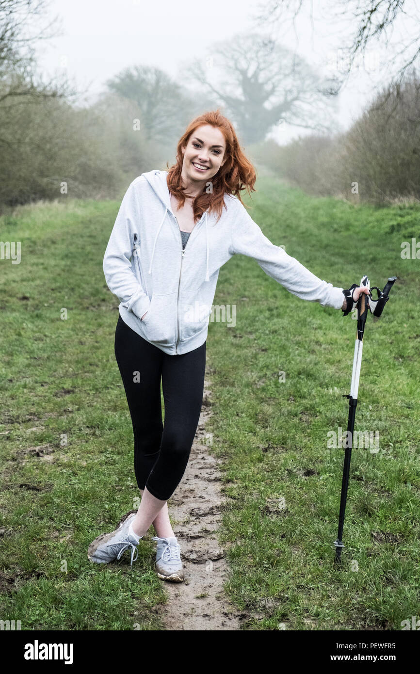 Young woman with long red hair wearing sportswear, exercising outdoors, looking at camera. Stock Photo