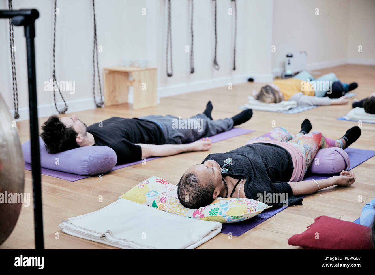 People lying down on an exercise studio floor relaxing after a sound therapy session Stock Photo