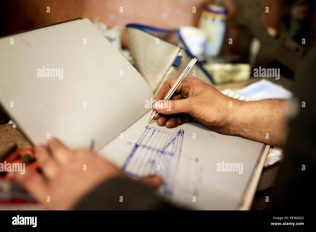An artisan metal worker drawing up designs for a gate in a sketchbook Stock Photo