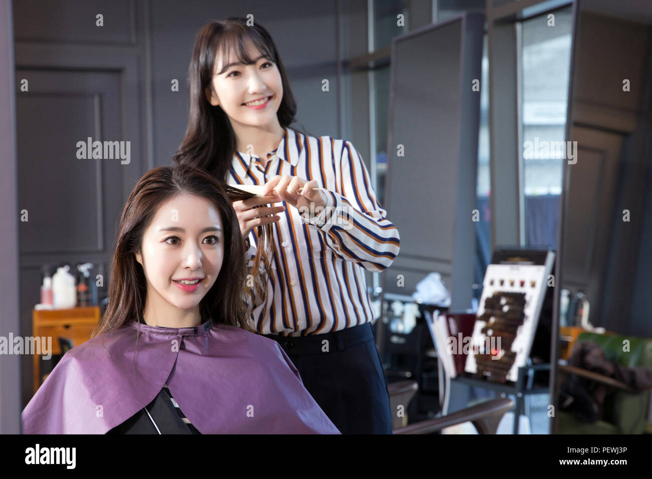 Hairdresser styling woman's hair in a salon. Korean beauty stock photo