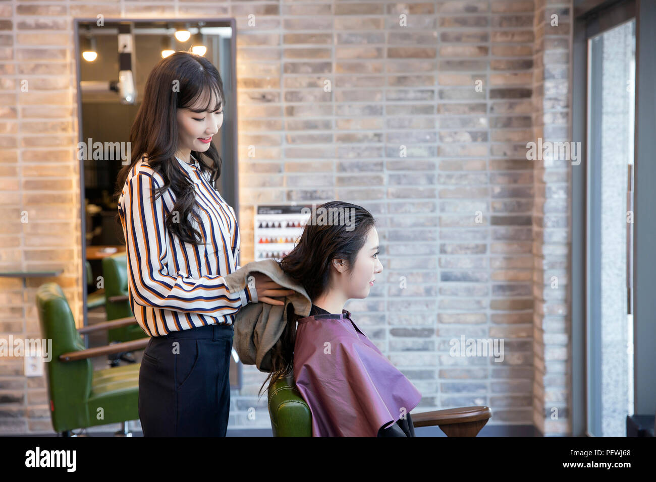 Hairdresser styling woman's hair in a salon. Korean beauty stock photo