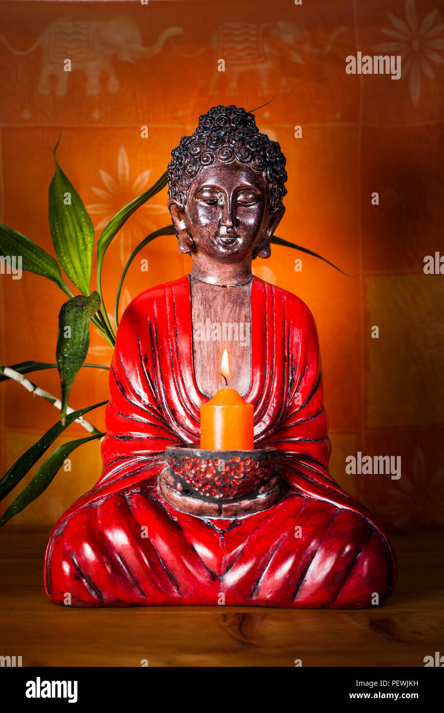 Zen buddha statue holding up a bright candle in the dark lighting up