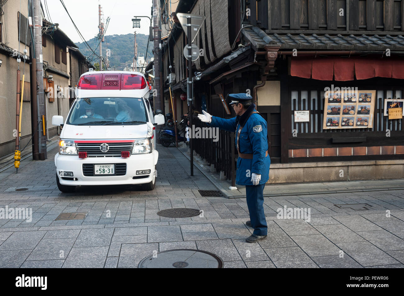 23.12.2017, Kyoto, Japan, Asia - A traffic warden is seen regulating the flow of traffic at an intersection in Kyoto's old city. Stock Photo