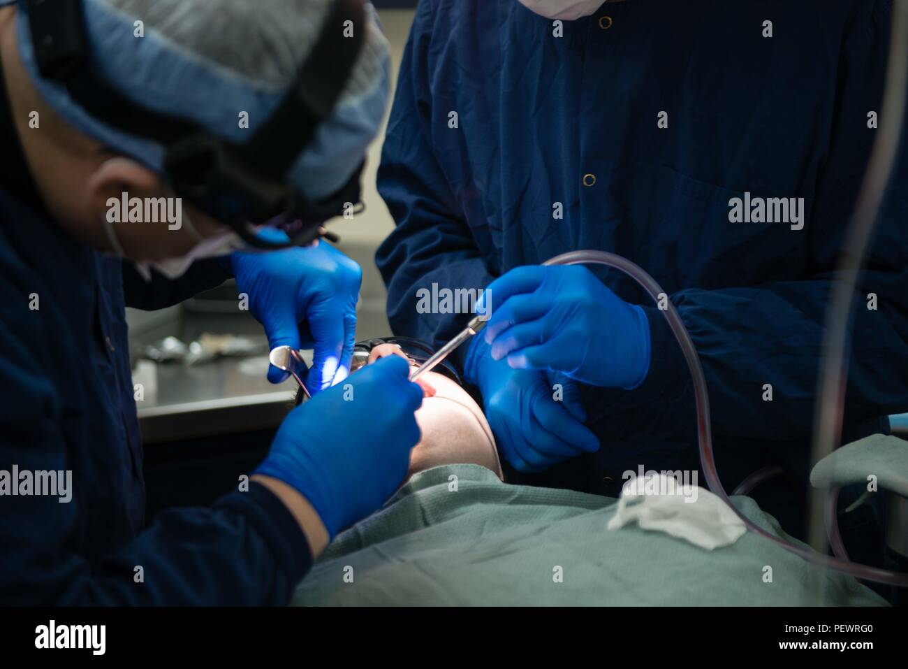 160209-N-MY174-033 PACIFIC OCEAN (Feb. 9, 2016) - Lt. Cmdr. Benjamin Lago, from Delitt, Mich., and Hospital Corpsman 1st Class Christopher Brown, from Portland, Ore., remove the wisdom teeth of Aviation Ordnanceman Airman Brian Deleon, from Jay, Okla., in USS John C. Stennis' (CVN 74) dental department. Providing a combat-ready force to protect collective maritime interests, Stennis is operating as part of the Great Green Fleet on a regularly scheduled Western Pacific deployment. (U.S. Navy photo by Mass Communication Specialist Seaman Tomas Compian / Released) Stock Photo