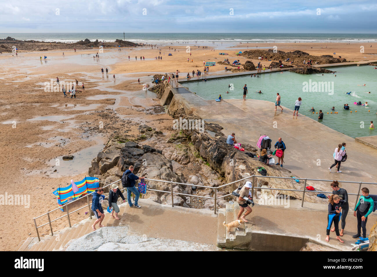 UK Weather - On a day of sunny spells with increasing cloud, the open air seapool on the seafront at Bude proves popular with holidaymakers, despite t Stock Photo
