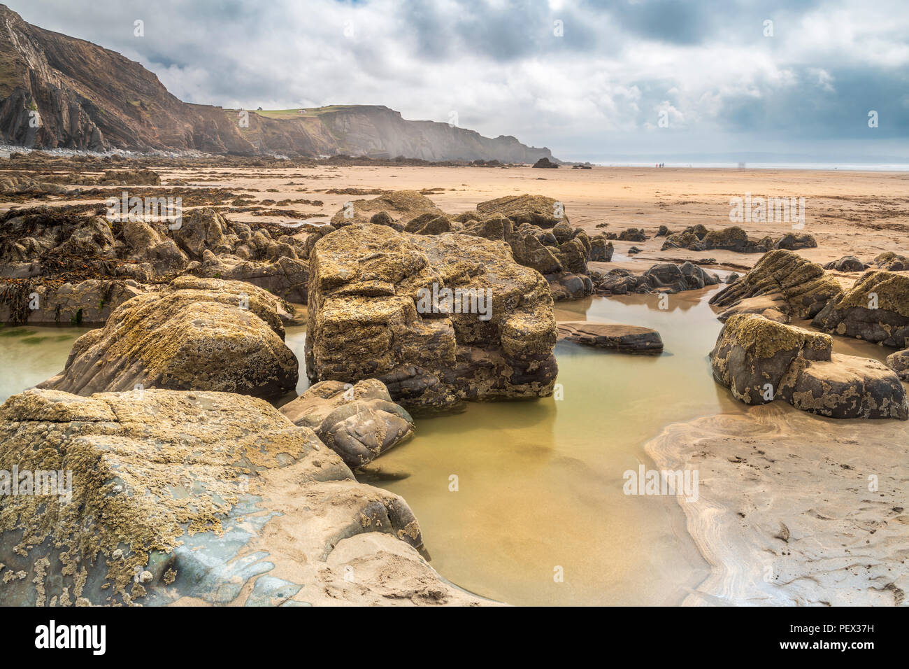 One of the many rock formations allows a deep pool to form on the expansive open beach at Sandymouth in North Cornwall. Stock Photo