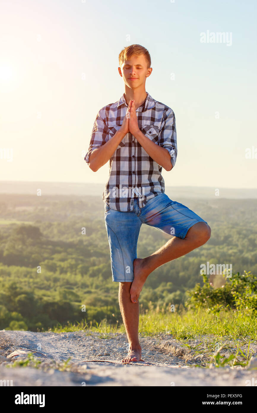 young man doing yoga outdoors in the sun health concept Stock Photo - Alamy