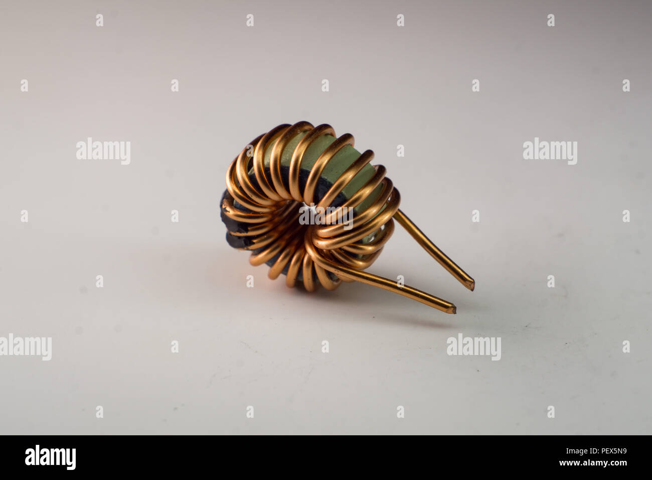 A small copper wire wrapped ferrite core choke with a simple white