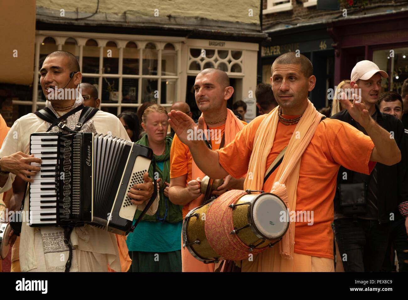 Hare Krishna members playing accordion and drum while chanting in the streets of York, North Yorkshire, England, UK. Stock Photo
