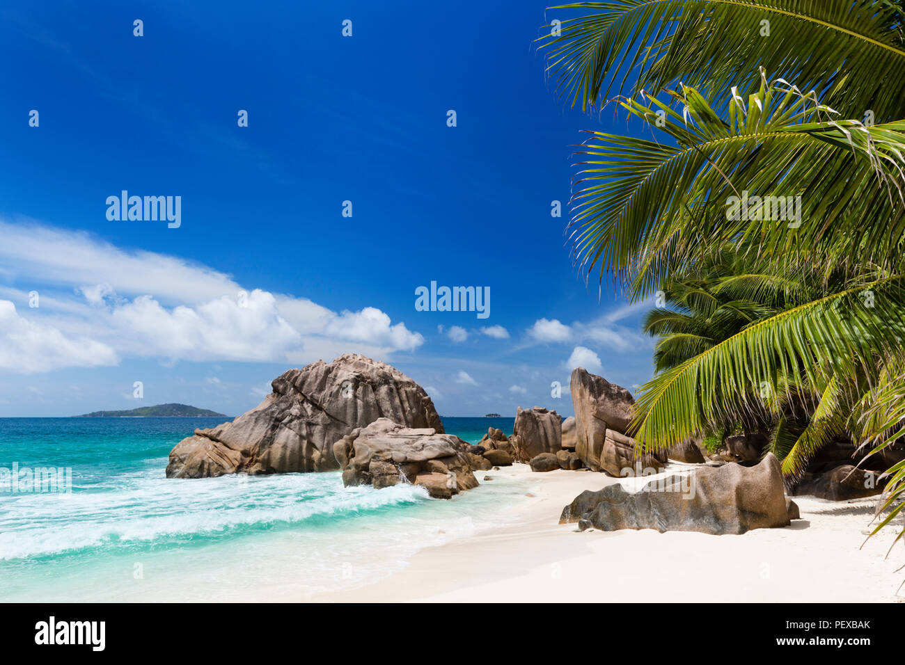 The beautiful tropical beach Anse Patates in La Digue, Seychelles with clear water, granite rocks and palm trees Stock Photo