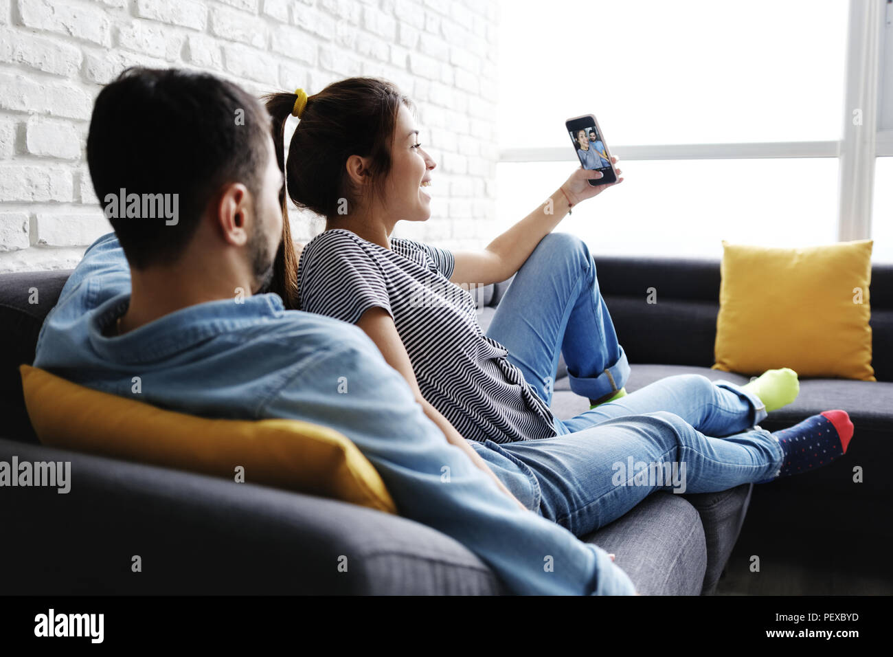 Young Couple Taking Selfie On Sofa At Home Stock Photo - Alamy