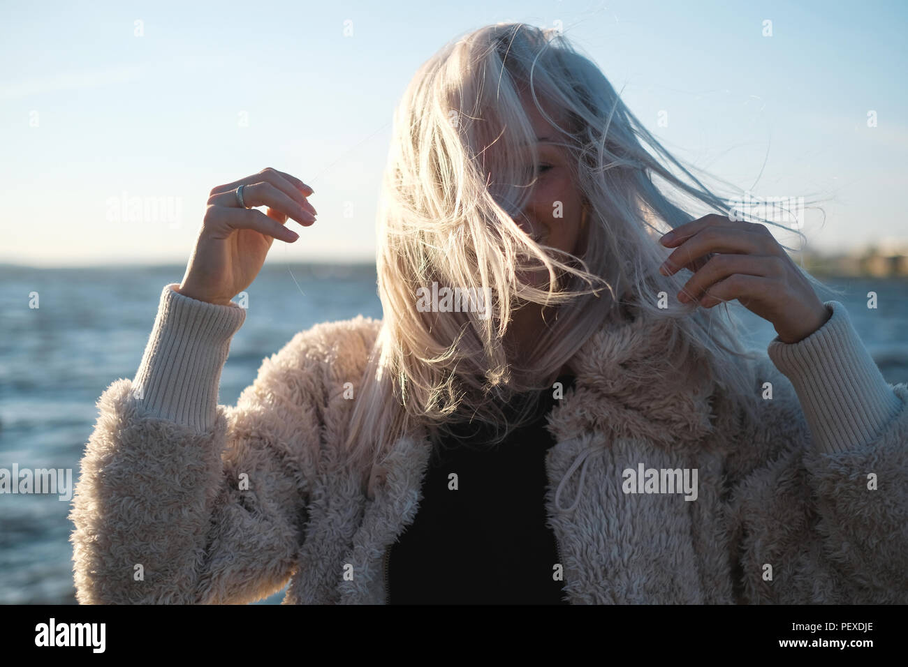 Lifestyle portrait of young blonde woman in windy day at sea Stock Photo