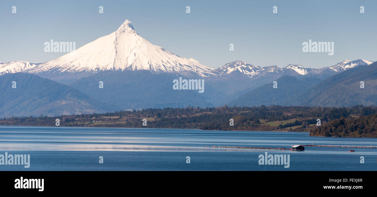 The snow-capped volcanic mountain of Puntiagudo rises behind Lago Rupanco lake in the Los Lagos region of Chile. Stock Photo