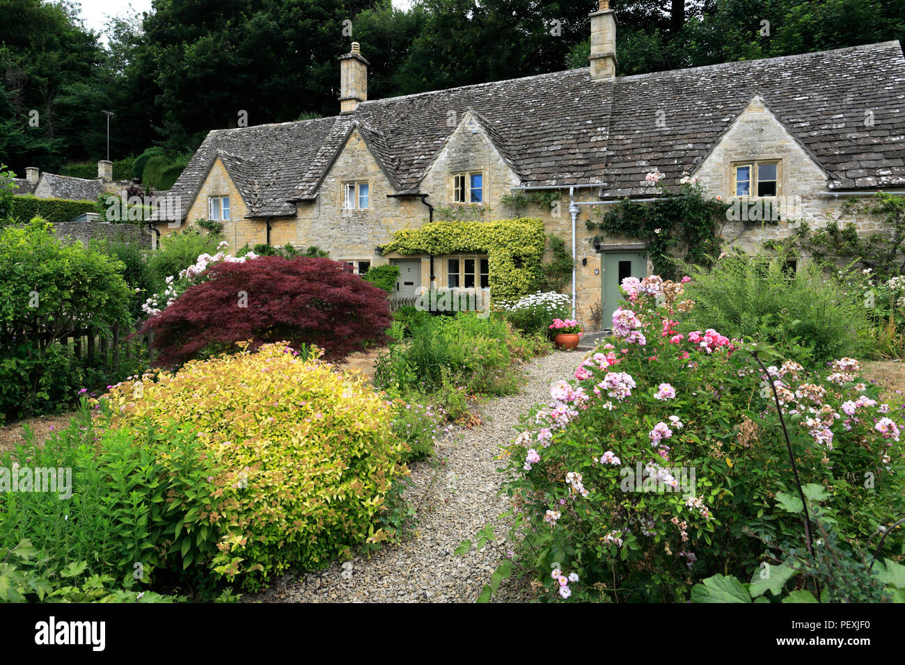 Stone Cottages with colourful gardens at Bibury village, Gloucestershire Cotswolds, England, UK Stock Photo