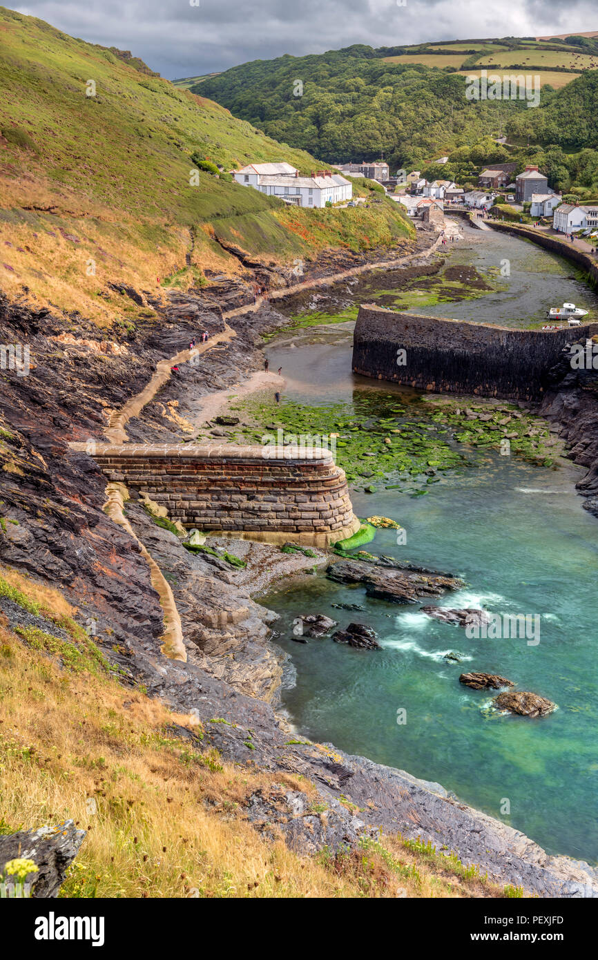 Tourists enjoy a brief respite from the persistent storms that pass over the picturesque little harbour at Boscastle on the North Cornish coast. Stock Photo