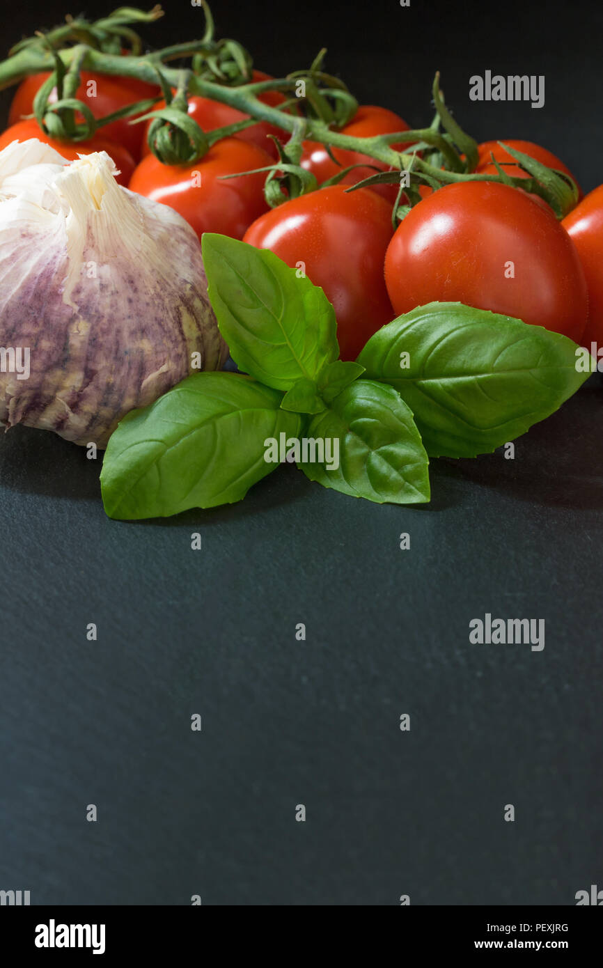 Low key shot of shrubs tomatoes, basil and garlic are lying on the ...