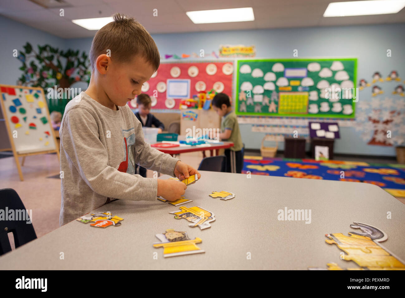 Schoolboy doing jigsaw puzzle in classroom Stock Photo