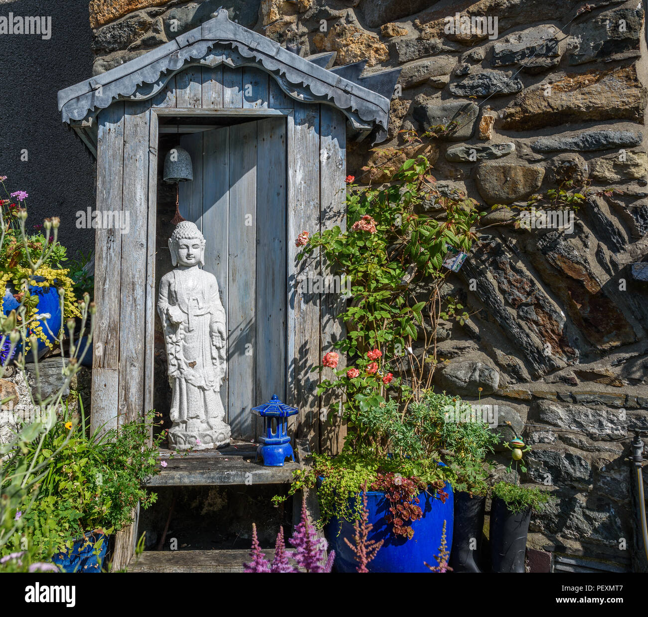 A small cottage garden with a statue of Buddha. Stock Photo