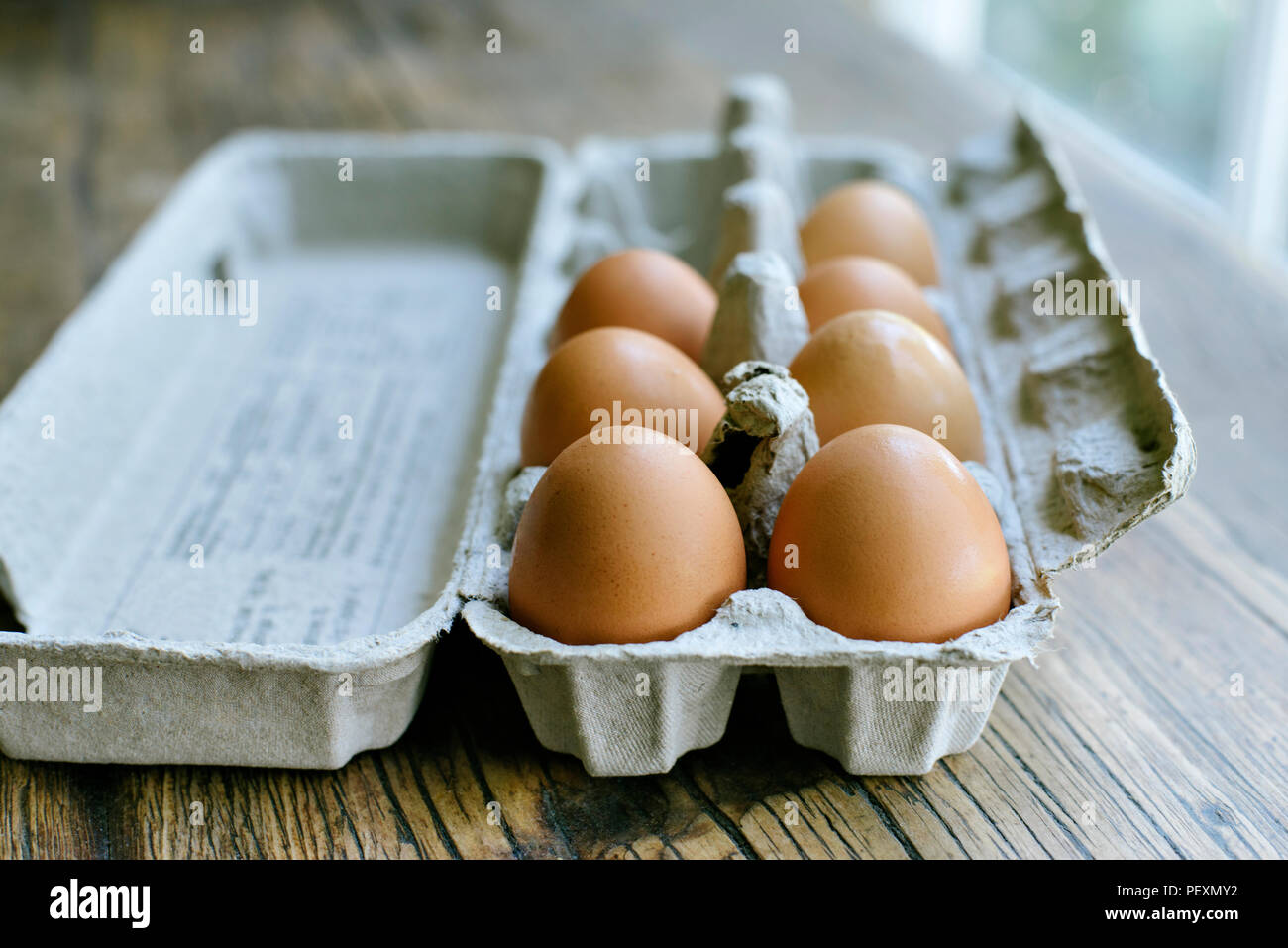 Fresh eggs in a carton on a farm table Stock Photo