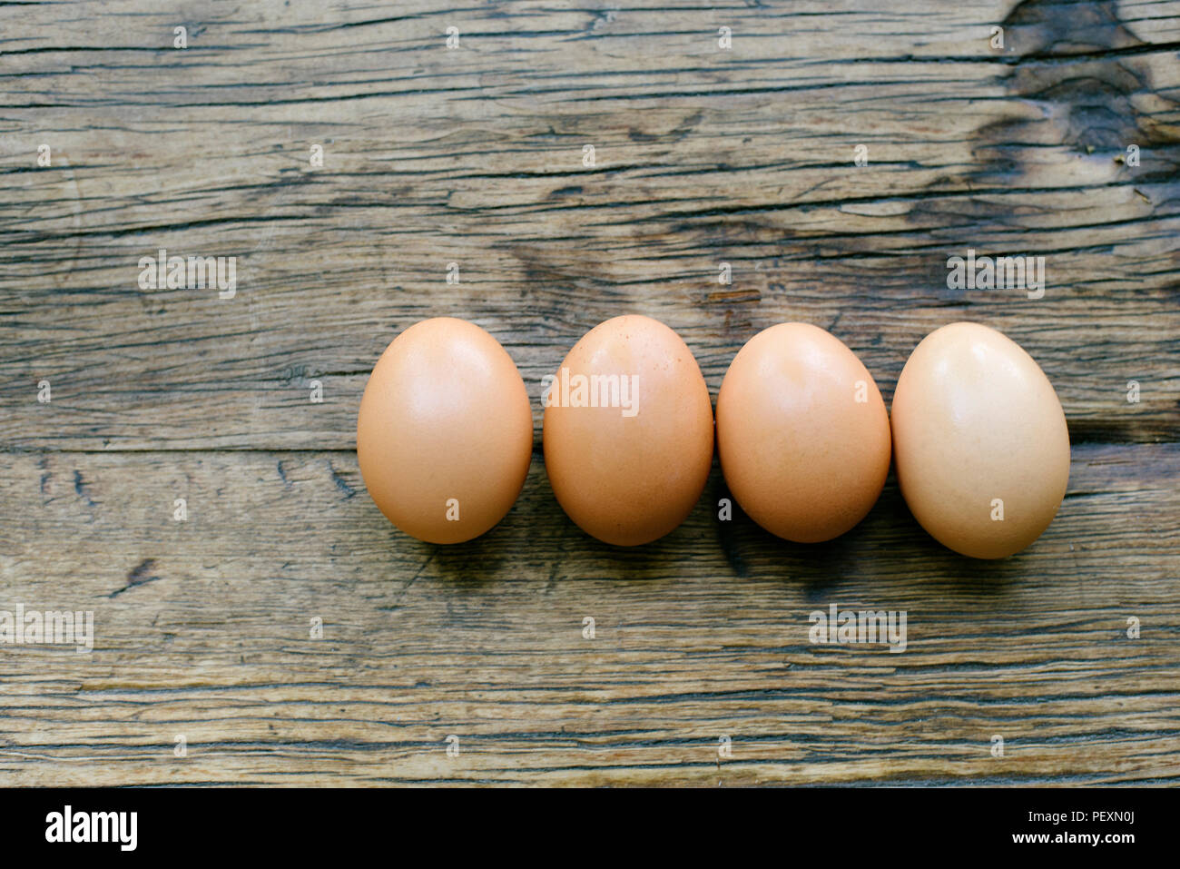 4 fresh eggs lined perfectly on a farm table Stock Photo