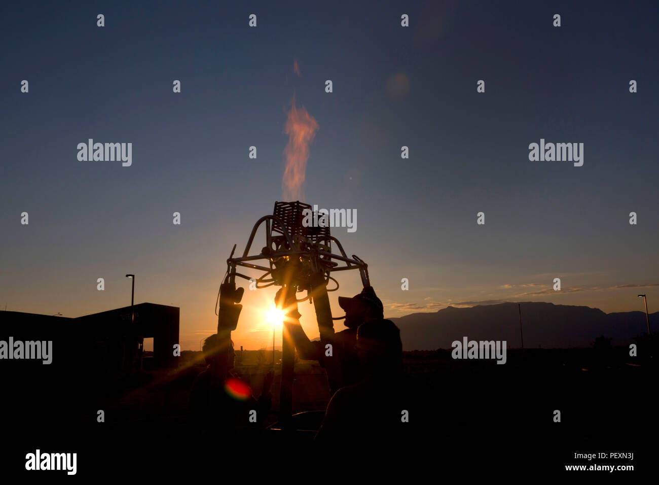 View of men operating hot air balloon burner at sunset, Albuquerque, New Mexico, USA Stock Photo