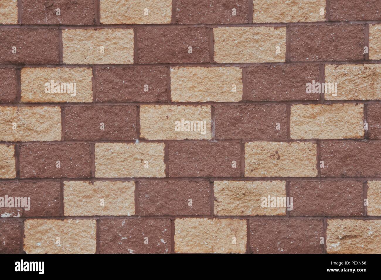 A pattern of brown and tan cement bricks on the facade of a building. Stock Photo