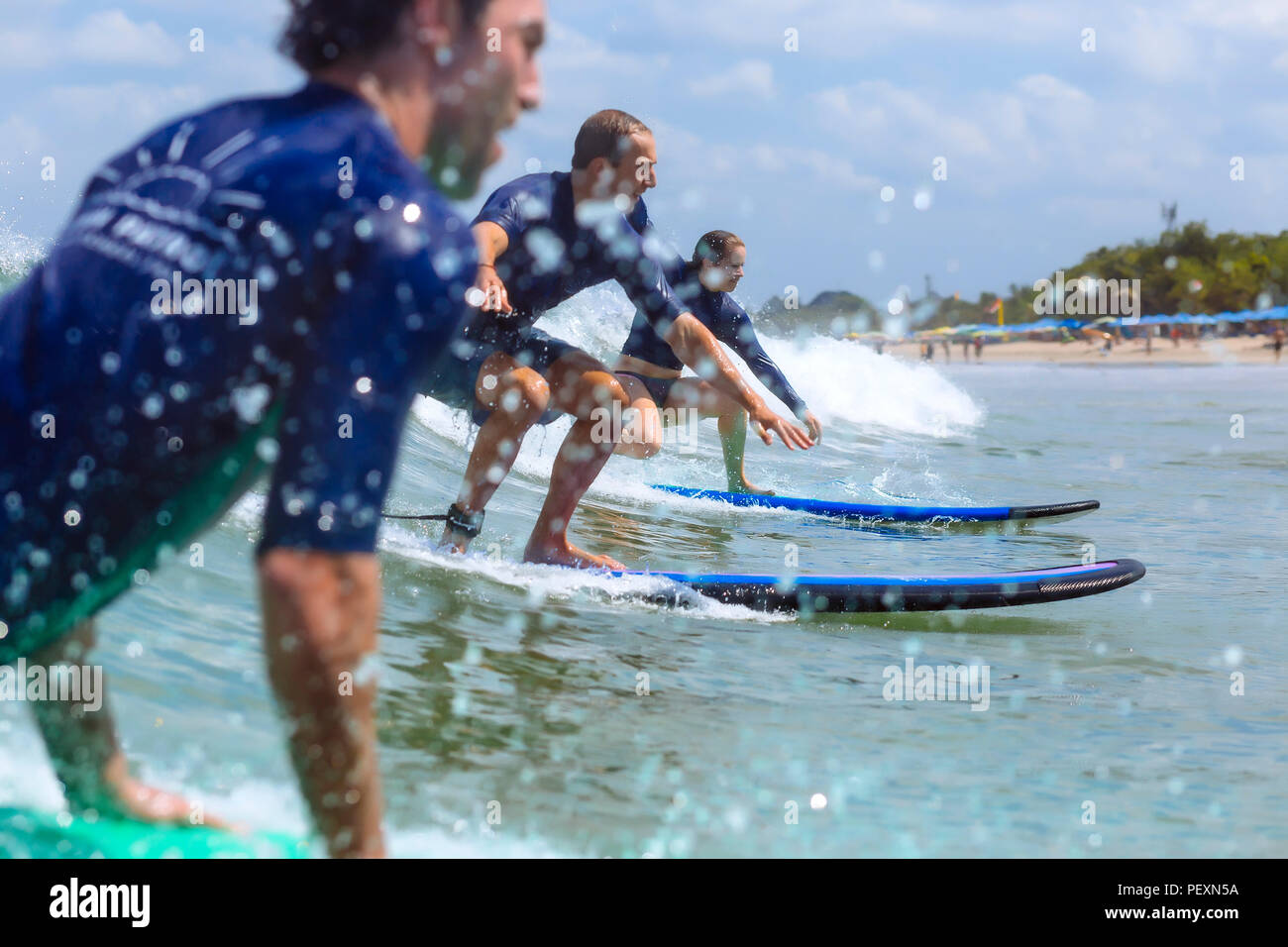 Three surfers riding wave Stock Photo